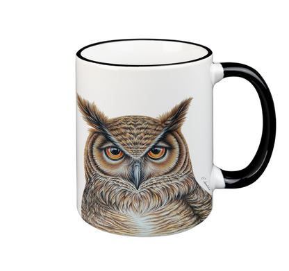 A white ceramic mug with a black rim and handle features a highly detailed, realistic illustration of an owl facing forward. The owl's feathers are colored in shades of brown and beige, and its intense eyes are vividly depicted. This Cuckoo's Nest Mug- Owl is both microwave safe and dishwasher safe.